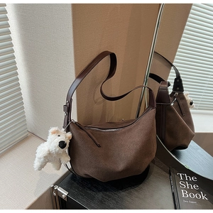 Detail of dark brown suede half-moon bag with leather strap and cute puppy pendant