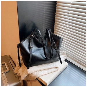 Detail of black faux leather tote bag showing oil-wax texture and metal hardware buckle