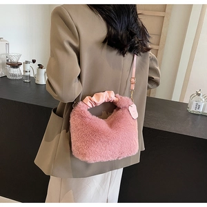 Detailed view of a pink plush crossbody bag with a satin ruffled handle and long strap