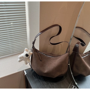 Close-up of matte brown dumpling bag texture with cute plush dog pendant detail