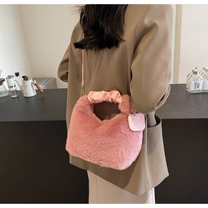 Rear view of a pink plush faux fur handbag with ruched handles worn by a model in a blazer