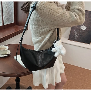 Detail of black PU hobo crossbody bag with cute plush bear charm on a female model