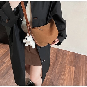 Brown suede crescent crossbody bag with white puppy pendant and adjustable strap