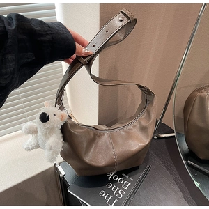 Detail of a brown textured leather hobo bag with adjustable strap and bear charm decoration