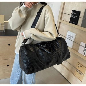 Dettaglio borsa da viaggio nera intrecciata con manici in pelle e tracolla regolabile