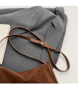Détail du sac bandoulière en daim marron avec sangle réglable et boucle en métal doré