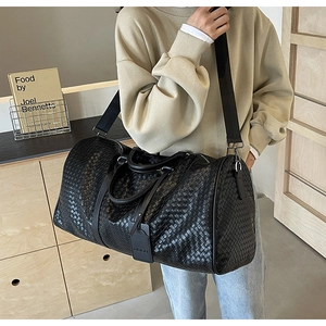 Dettaglio borsa da viaggio in pelle intrecciata nera con manici rinforzati e fibbie argento