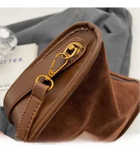 Gros plan sur la boucle dorée vintage et la texture en daim marron du petit sac