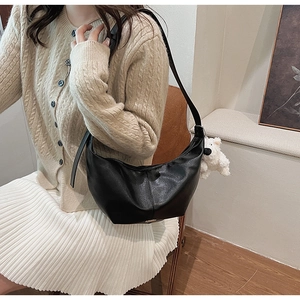 Detail of black crescent crossbody bag with sheep plush charm on model