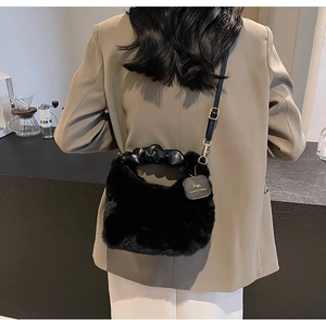 Detail of black faux fur bag featuring a ruched handle and adjustable gold metal buckle