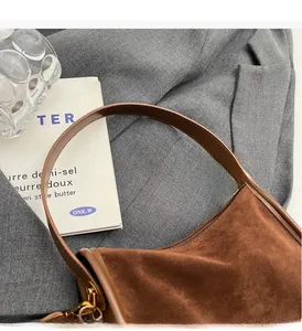 Détail du sac à main en daim marron foncé avec poignée ronde et finitions dorées