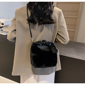 Detail of black faux fur plush handbag with gathered leather handle and gold hardware