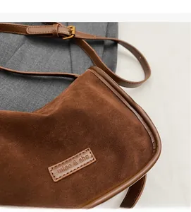 Gros plan du sac bandoulière en daim marron avec logo miao & she et couture fine