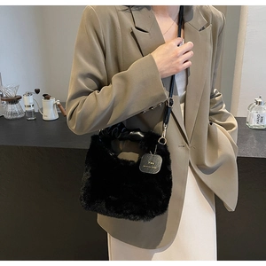 Detail of plush black faux fur handbag with leather strap and gold tone YOU tag