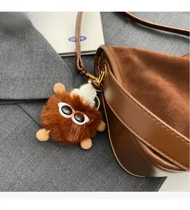 Gros plan du charm monstre en peluche avec lunettes sur un sac bandoulière vintage