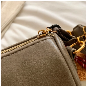 Detailed close-up of premium pebbled leather texture and vintage gold hardware on bag