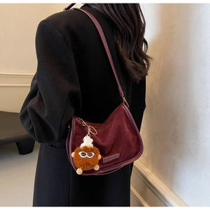 Détail du sac bandoulière croissant en daim bordeaux avec charm monstre brun