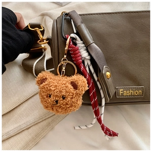 Detail of plush brown bear keychain with golden metal clasp on a stylish Boston handbag