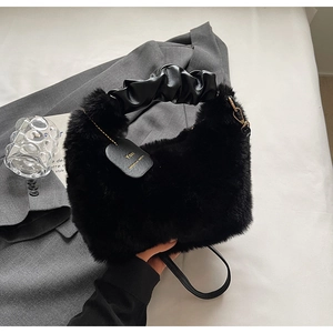 Close-up of black plush handbag with ruched leather handle and small You tag