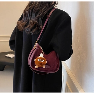 Détail du sac hobo en velours bordeaux avec un joli charme de monstre en peluche