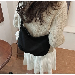 Detail of black crescent hobo bag with cute white plush charm on a knit sweater outfit