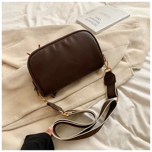 Detail view of brown PU leather Boston bag with wide woven strap and gold metal buckles