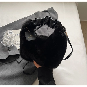 Detail of black faux fur handbag with leather scrunchie handle and gold engraved tag