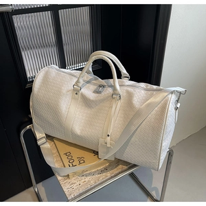 Dettaglio della trama in pelle intrecciata bianca di una borsa da viaggio con zip metallica