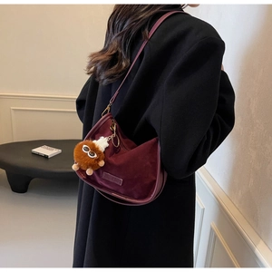 Détail du sac hobo en daim bordeaux avec un charmant monstre en peluche marron sur le côté