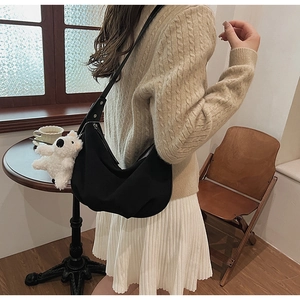 Close-up of black matte crescent crossbody bag featuring a cute white teddy bear pendant