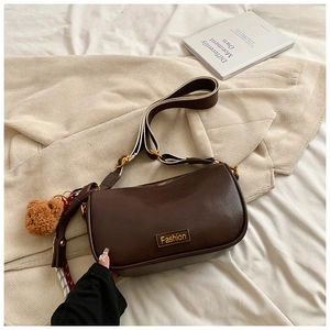 Detail of brown Boston bag with Fashion text, wide strap and cute plush bear charm
