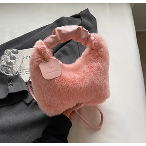 Detail of pink faux fur handbag featuring scrunchie handle and motivational tag