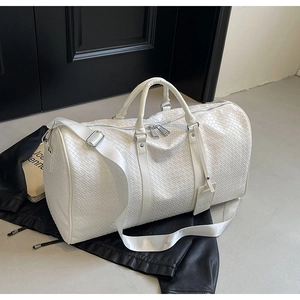 Dettaglio della grande borsa da viaggio bianca intrecciata con manici e tracolla