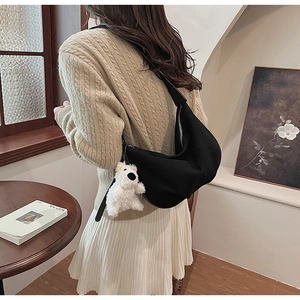 Detail of black crescent crossbody bag in nylon with white plush bear charm and silver zipper