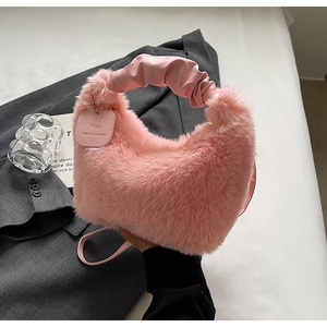 Detail of pink faux fur cloud bag with ruched handle and leather brand tag decoration