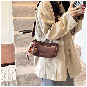 Detail of dark brown Boston bag with Fashion gold label and plush bear charm