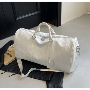 Dettaglio della borsa da viaggio bianca intrecciata con zip argento e logo NOCO