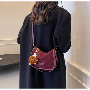 Détail du sac selle en daim bordeaux avec charm monstre en peluche et boucle dorée