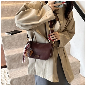 Detail of dark brown Boston bag featuring golden Fashion logo and cute bear pendant