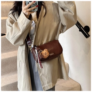 Detail of deep brown Boston bag with Fashion plaque, plush bear charm and tassel
