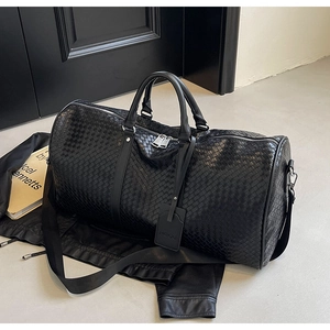 Dettaglio della borsa da viaggio in pelle intrecciata nera con fibbie metalliche lucide
