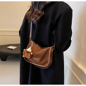 Gros plan sur un sac bandoulière rétro en daim marron avec charme en peluche