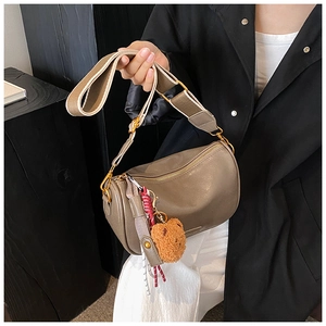 Close-up of brown leather Boston bag featuring wide strap and cute plush bear charm