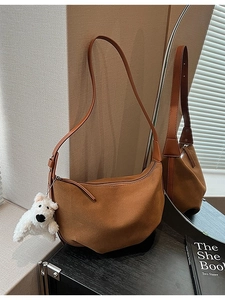 Brown matte suede half-moon crossbody bag with leather strap and plush dog charm