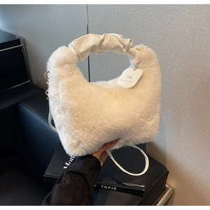 Detail of white faux fur handbag featuring a plush texture and ruched leather handle