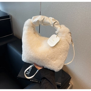 Detail of white faux fur handbag featuring gold chain accents and pleated leather handle