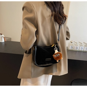 Sac bandoulière en daim noir avec pendentif ours en peluche sur blazer kaki