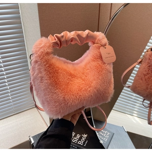 Detail of pink faux fur handbag with ruched leather handle and engraved slogan tag