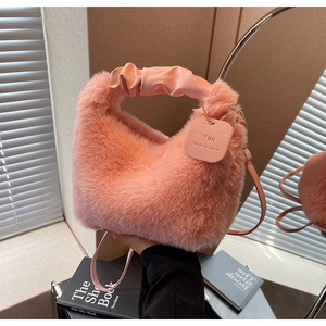Detail of pink plush faux fur handbag with ruched leather handle and small shoulder strap