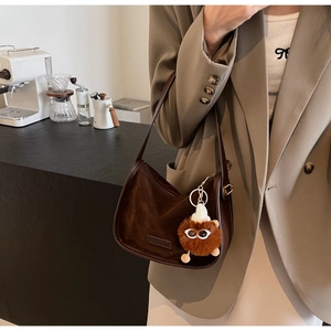 Gros plan sur le sac croissant en daim marron avec un porte-clé monstre en peluche original